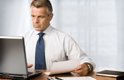 Businessman at Desk with Computer and Paperwork