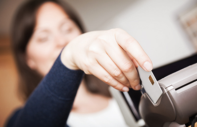 Close up of a woman hand sliding a credit card through the card reader.. Focus is on the hand.
