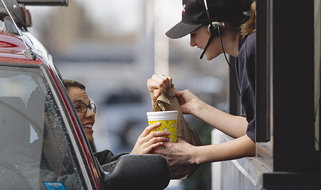 A fast-food employee gives a customer her order